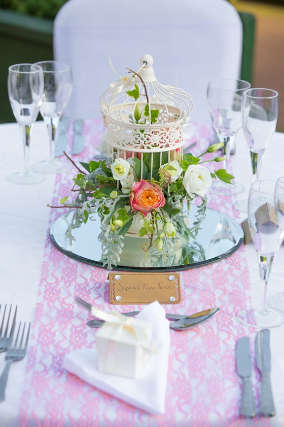 a table topped with a birdcage filled with flowers.