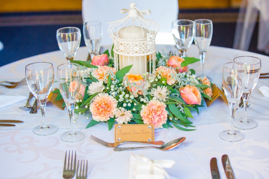 a table topped with a white birdcage filled with flowers.