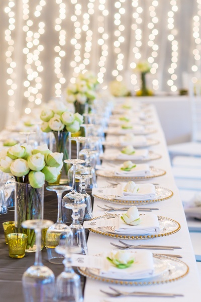 a long table is set with white and green flowers.