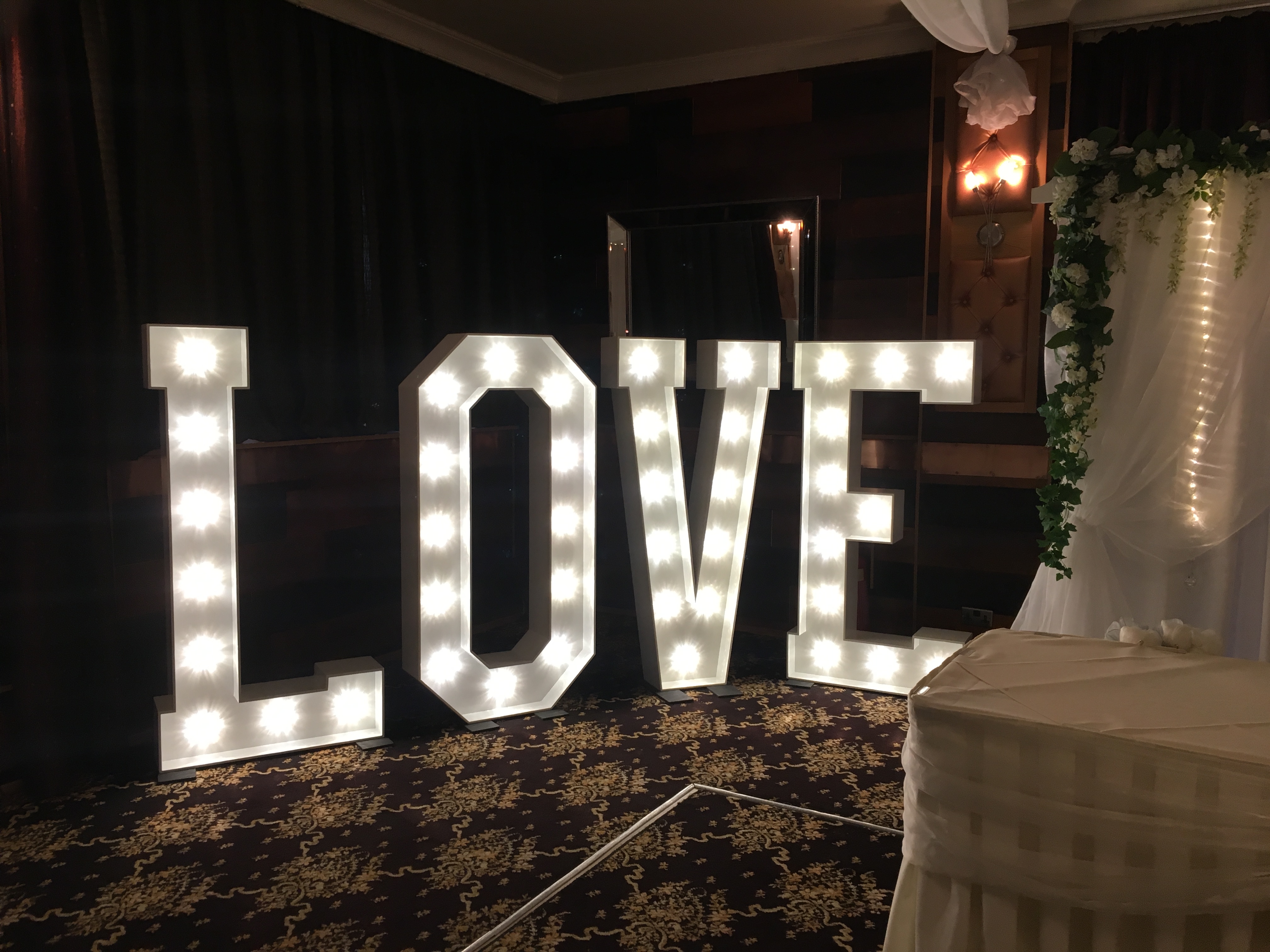 a lighted love sign sitting on top of a carpeted floor.