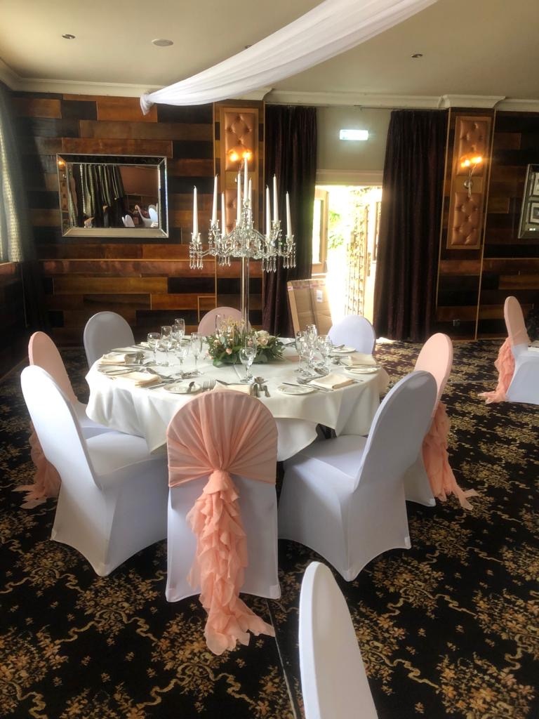 a banquet table with white chairs and pink sashes.