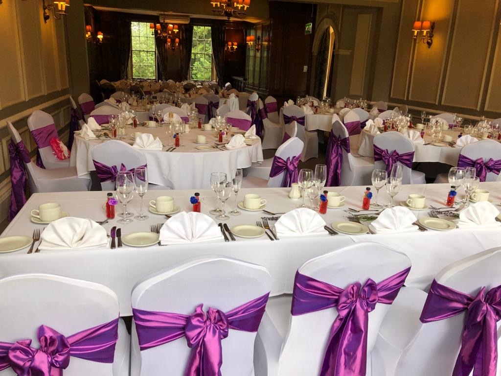 a room filled with white tables covered in purple sashes.