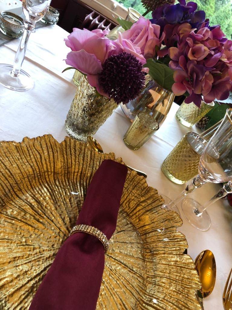 a table topped with gold plates and vases filled with flowers.