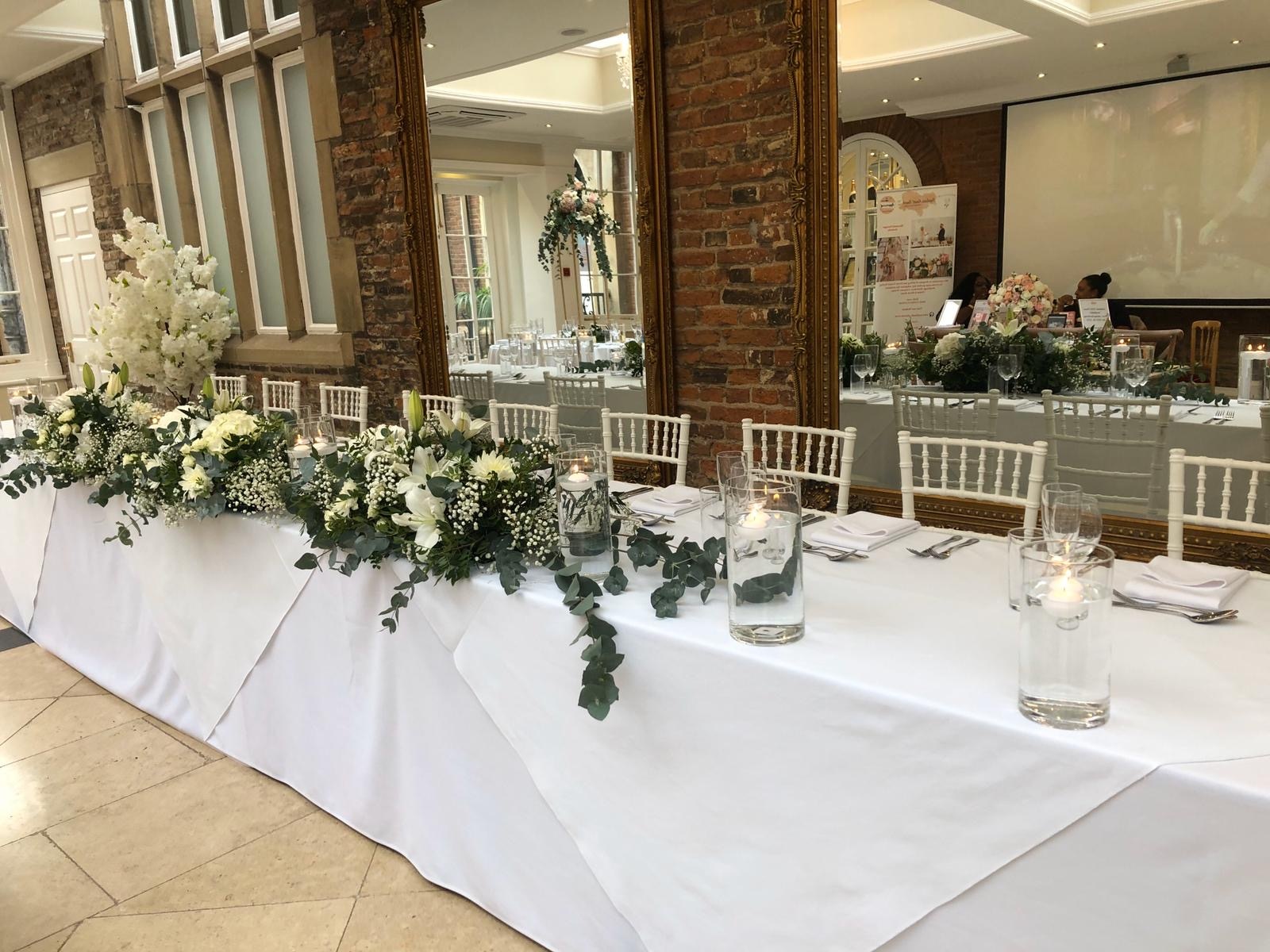 a long table with white flowers and greenery.