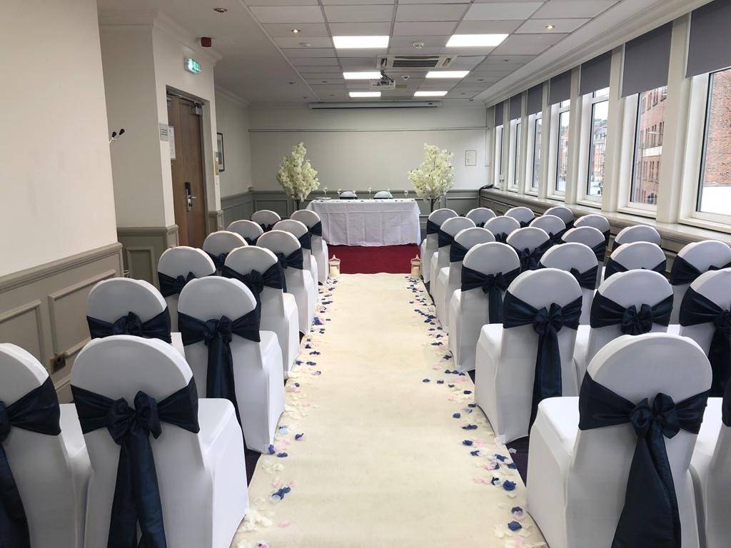 rows of white chairs with black bows on them.