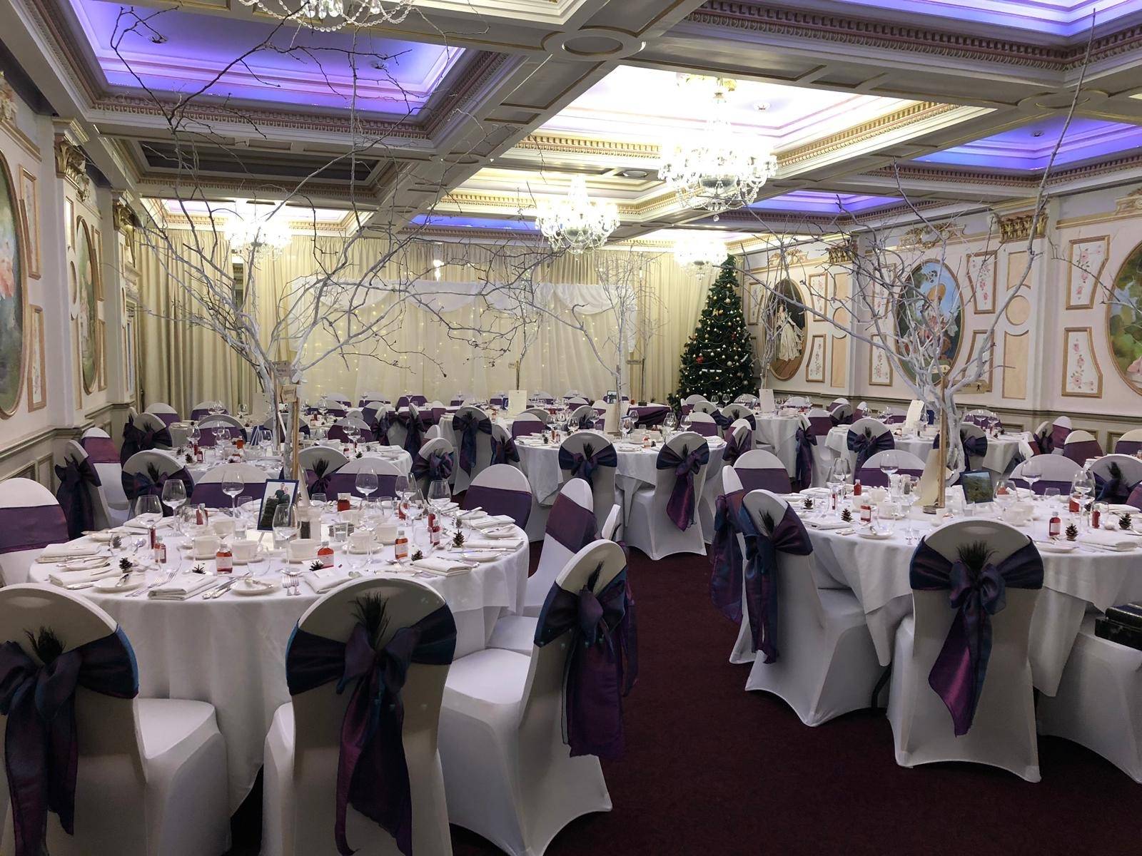 a room filled with tables covered in white and purple cloths.