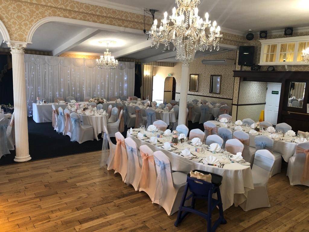 a room filled with tables and chairs covered in white linens.