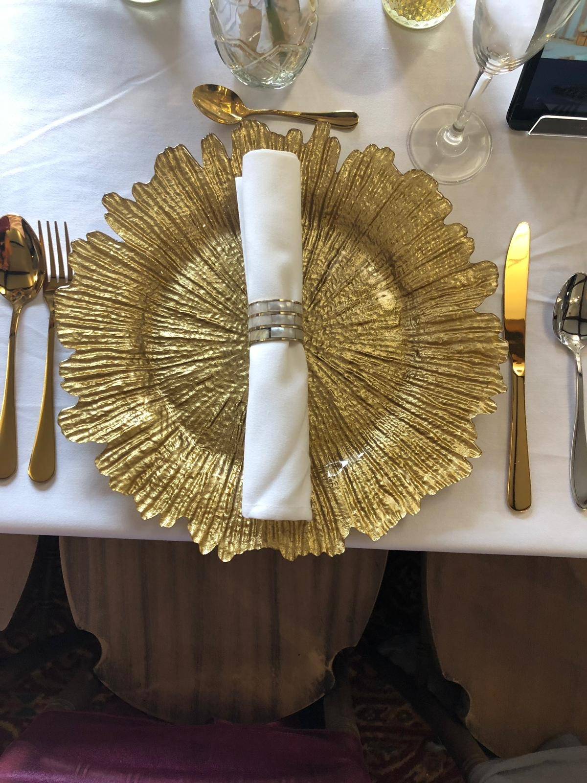 a white table with a gold plate and silverware.