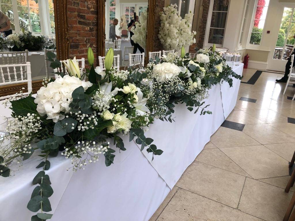 a long table with white flowers and greenery.