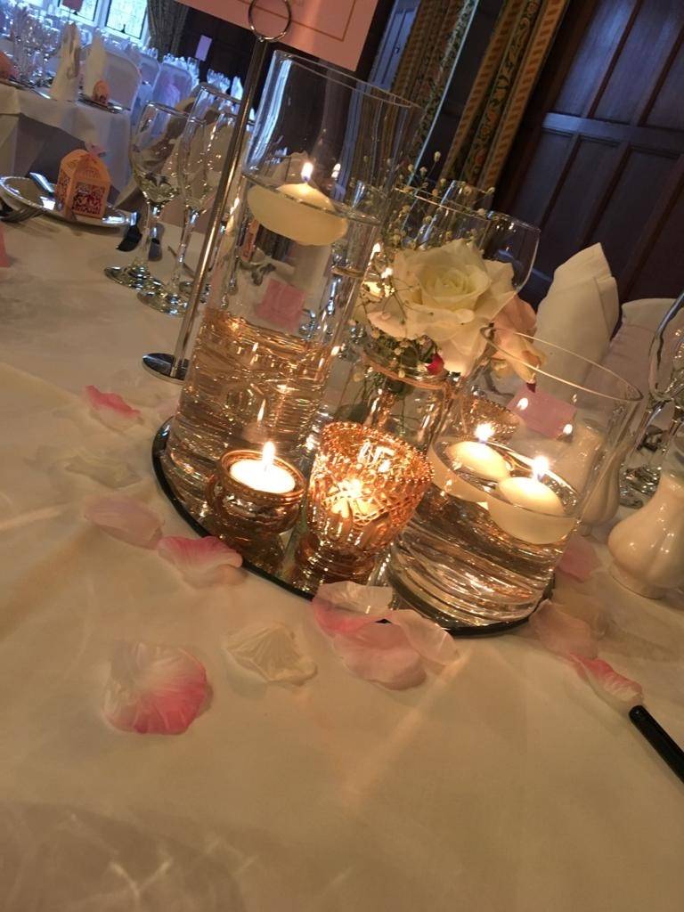 a table topped with lots of glass vases filled with candles.