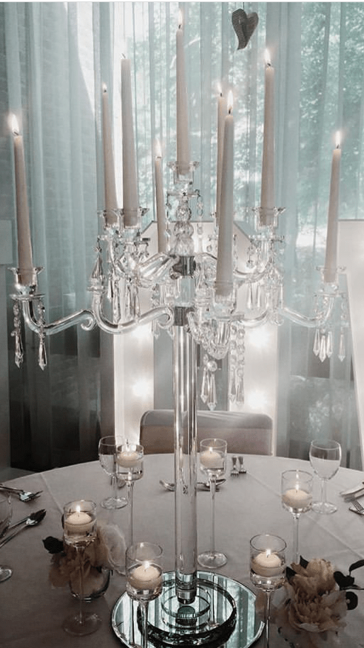 a dining room table with a chandelier and candles.