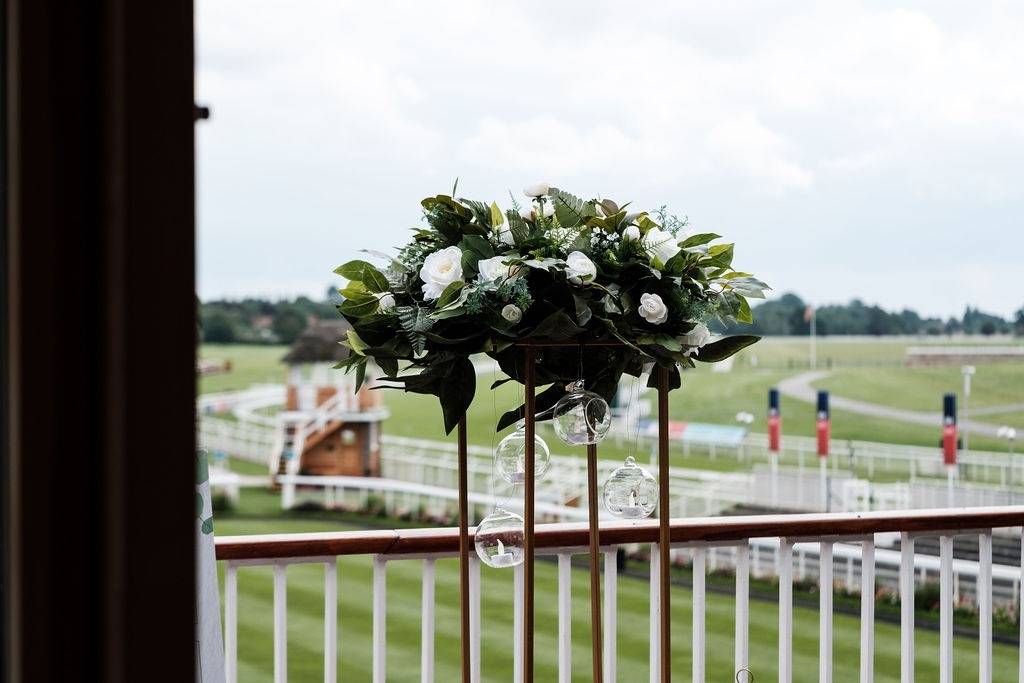 a vase with flowers on a balcony overlooking a race track.