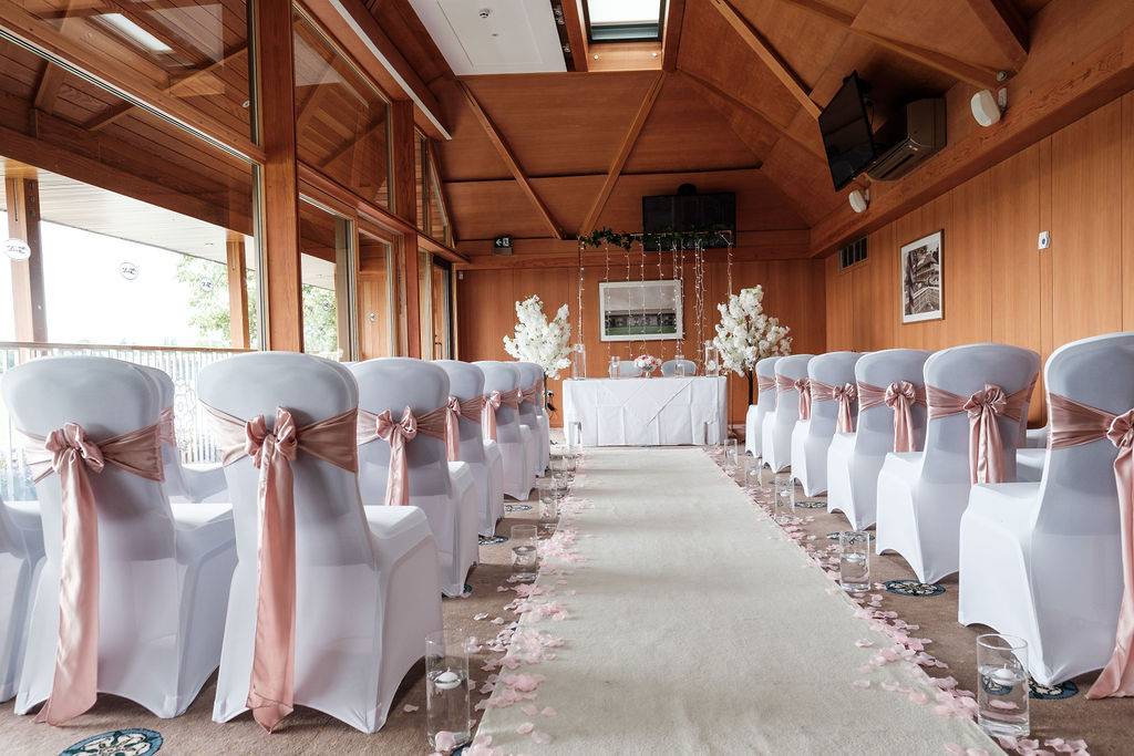 a row of white chairs with pink sashes.