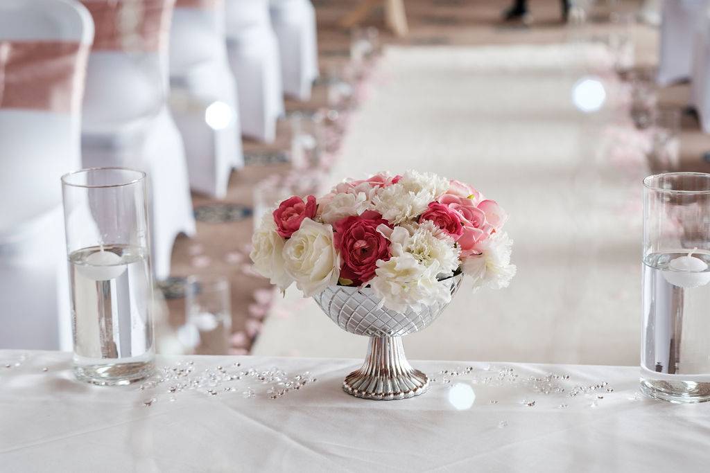 a vase filled with white and red flowers next to a glass of water.