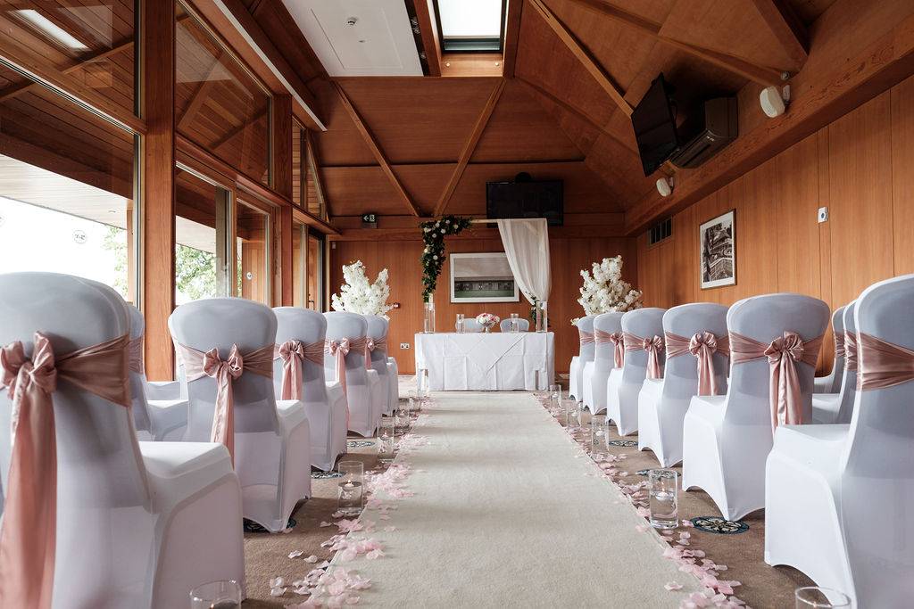 a row of white chairs with pink sashes on them.