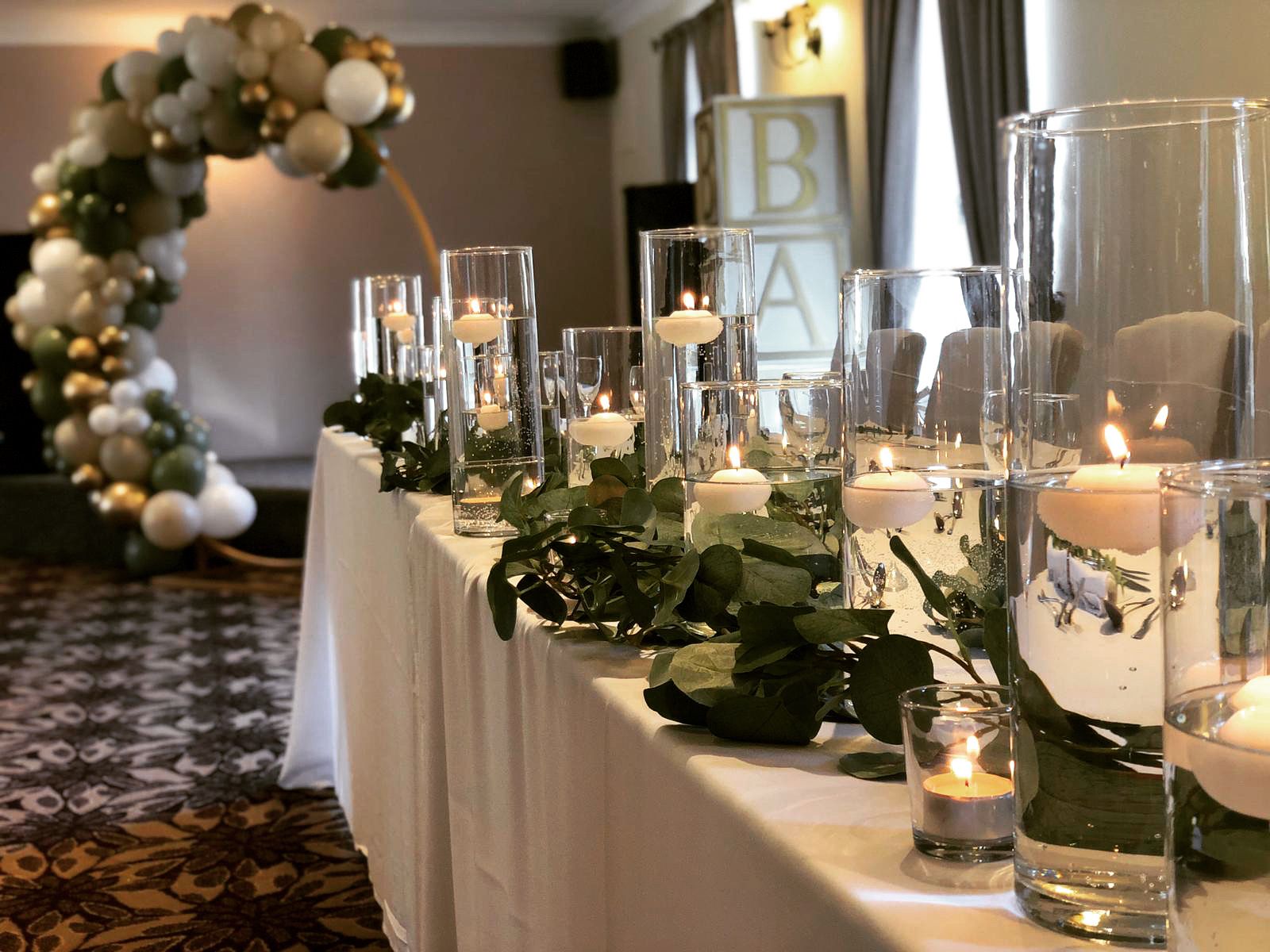 a long table with candles and greenery on it.