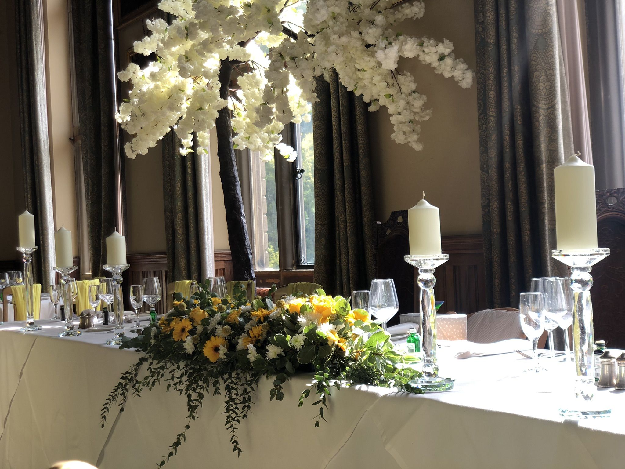 a table topped with lots of white and yellow flowers.