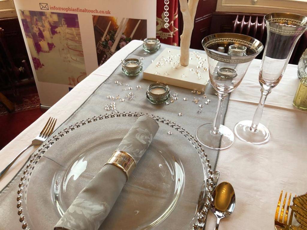 a place setting with a napkin, silverware, and a bottle of wine.