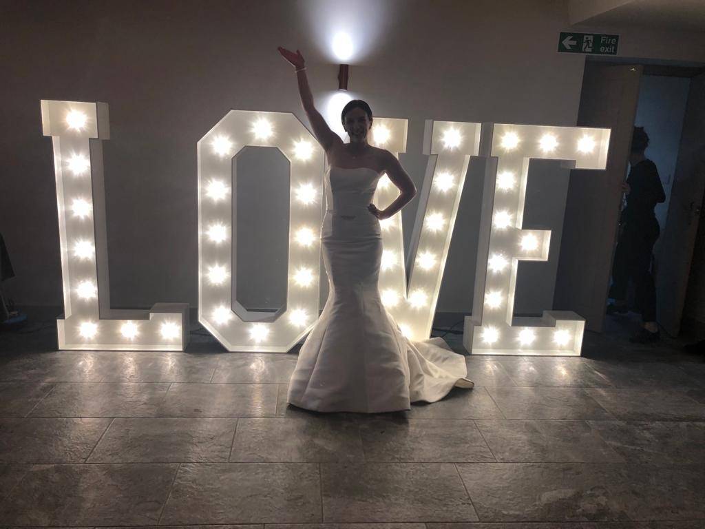 a woman in a wedding dress standing in front of a love sign.