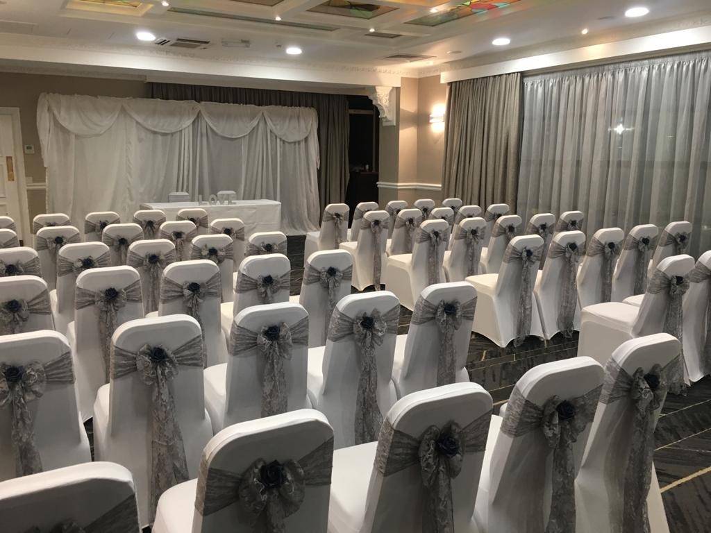 a room filled with lots of white chairs covered in bows.