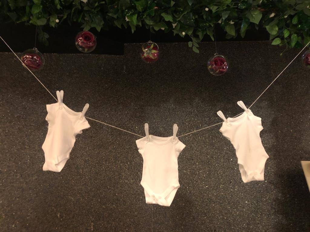 a baby's bodysuit hanging on a clothes line.