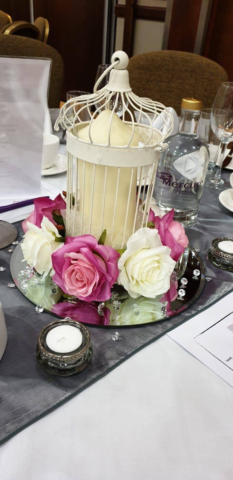 a table topped with a birdcage filled with flowers.