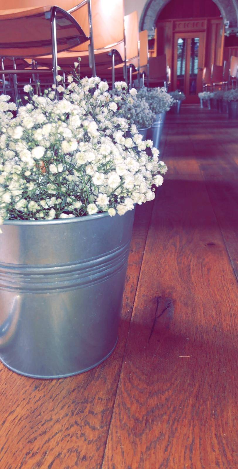 a metal bucket filled with white flowers on top of a wooden floor.