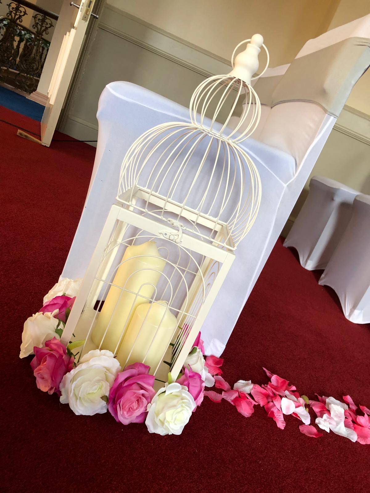 a white birdcage filled with candles and flowers.