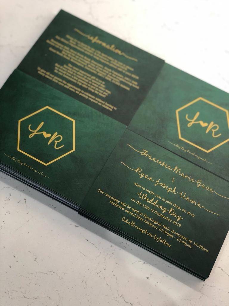 a close up of a green and gold wedding card.
