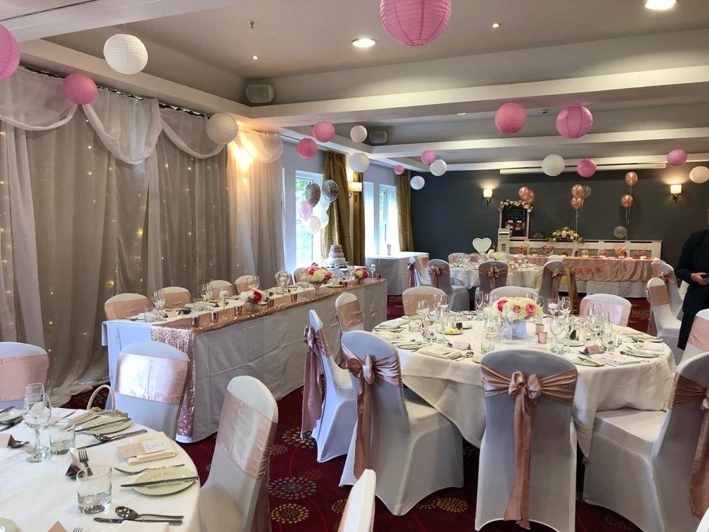 a room filled with lots of tables covered in white and pink decorations.
