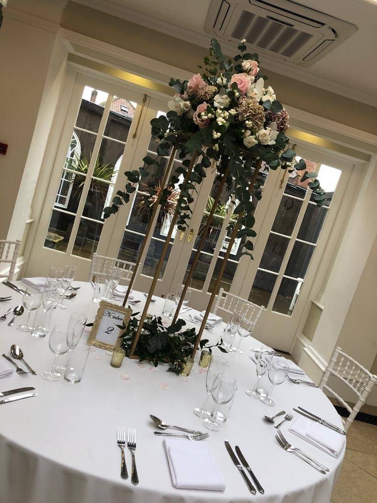 a table with a tall centerpiece with flowers on it.