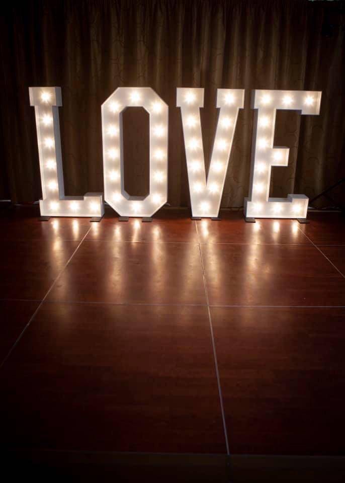 a light up love sign on a wooden floor.