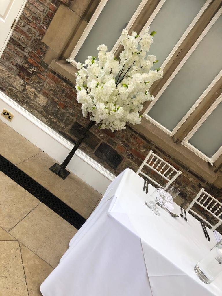 a tall vase of white flowers on top of a table.