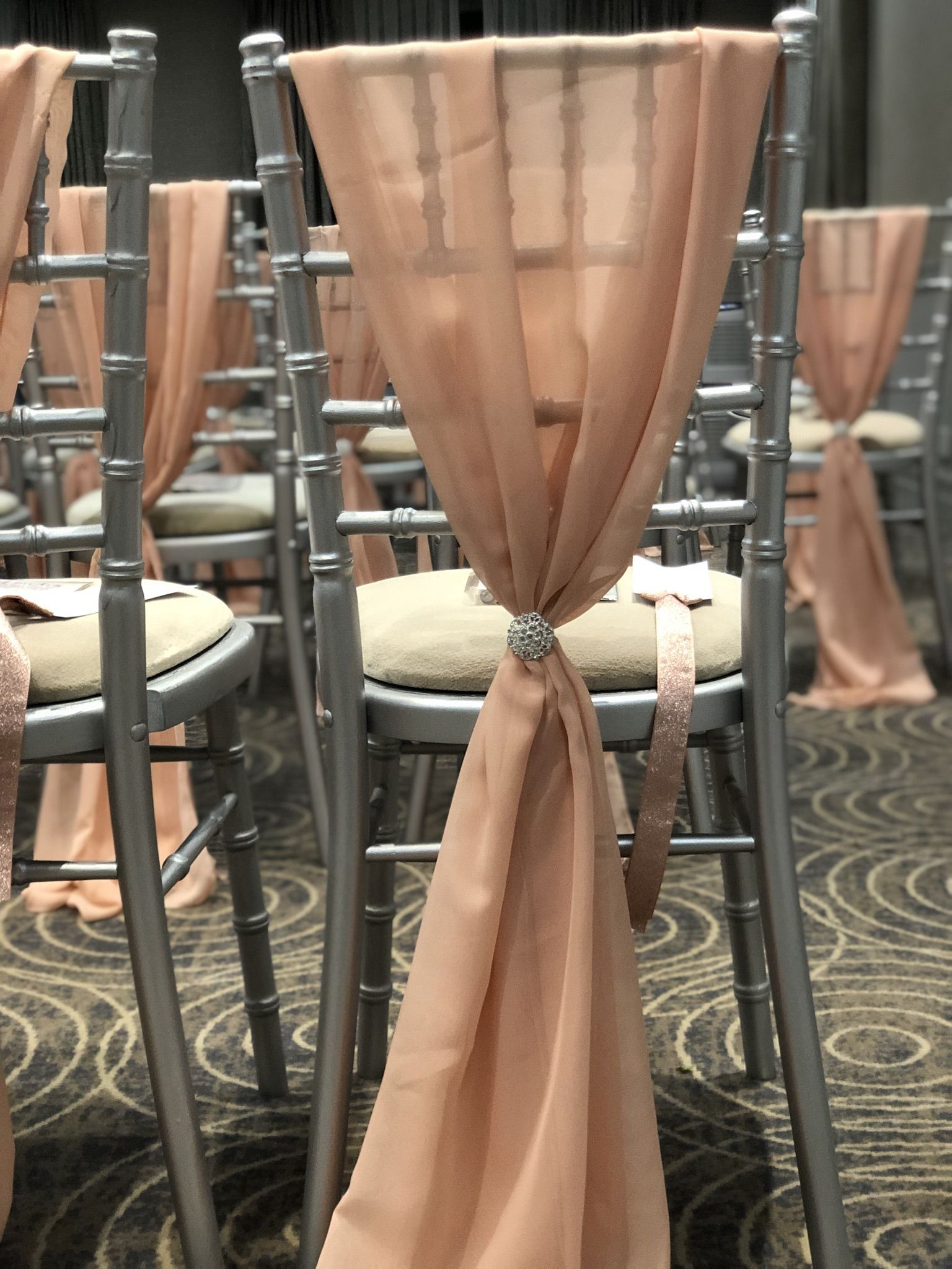 a row of chairs with pink sashes on them.