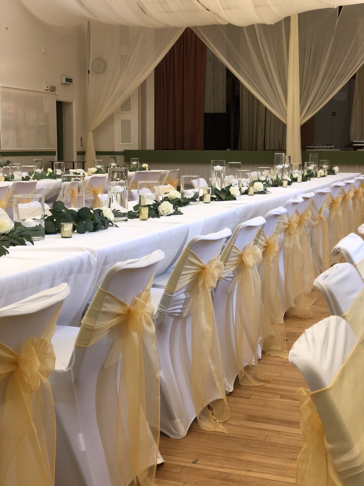 a banquet hall with tables covered in white and yellow cloths.