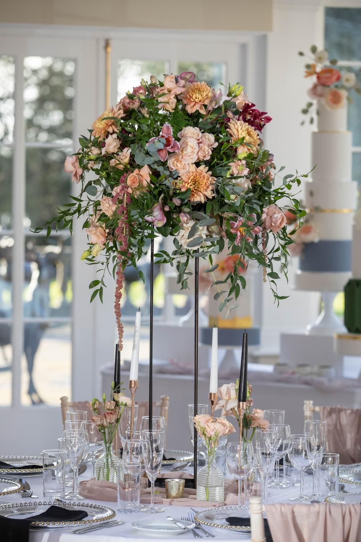 a centerpiece with flowers and candles on a table.