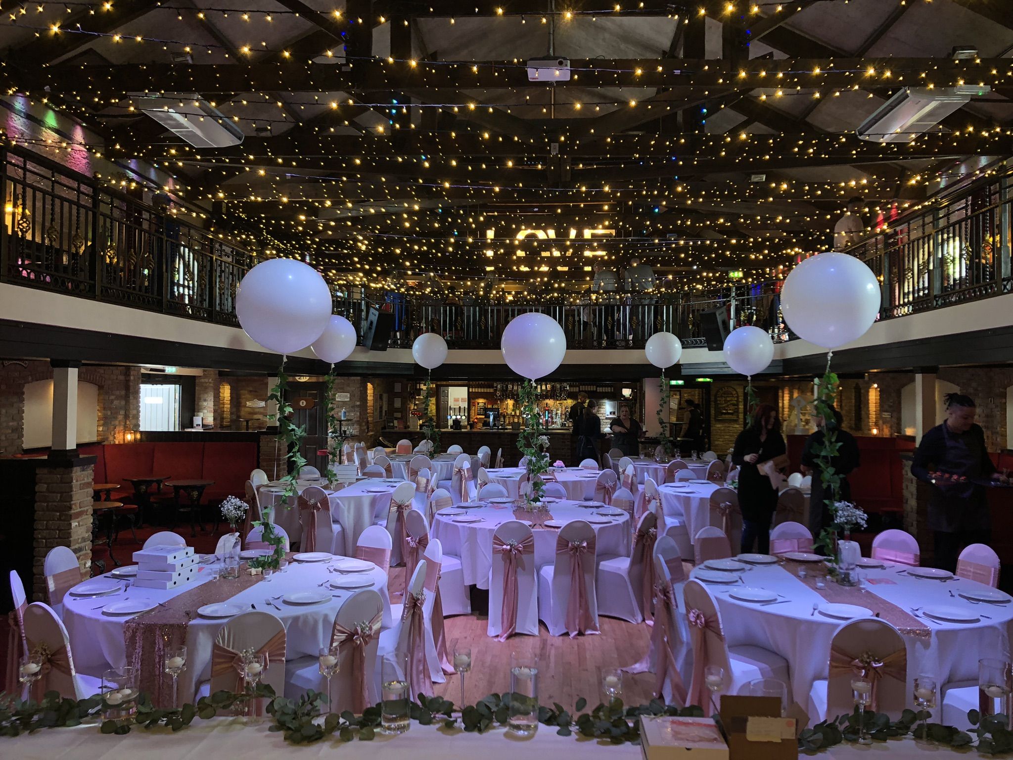 a room filled with tables and chairs covered in white tablecloths.
