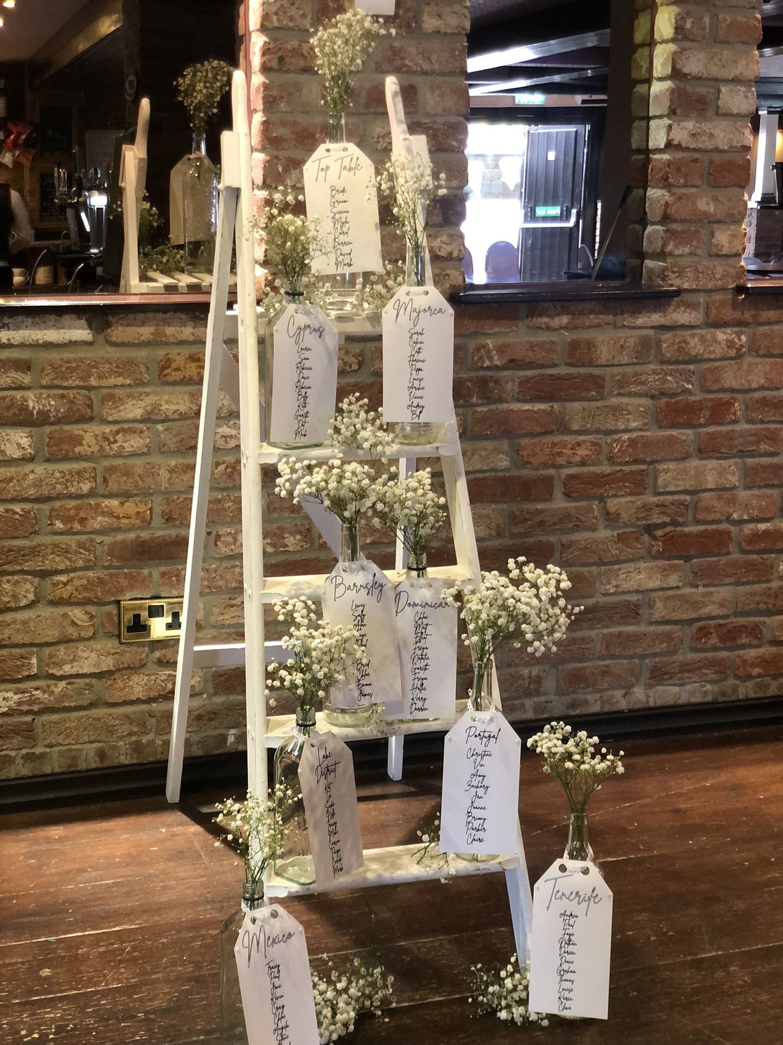 a white ladder with flowers and place cards on it.