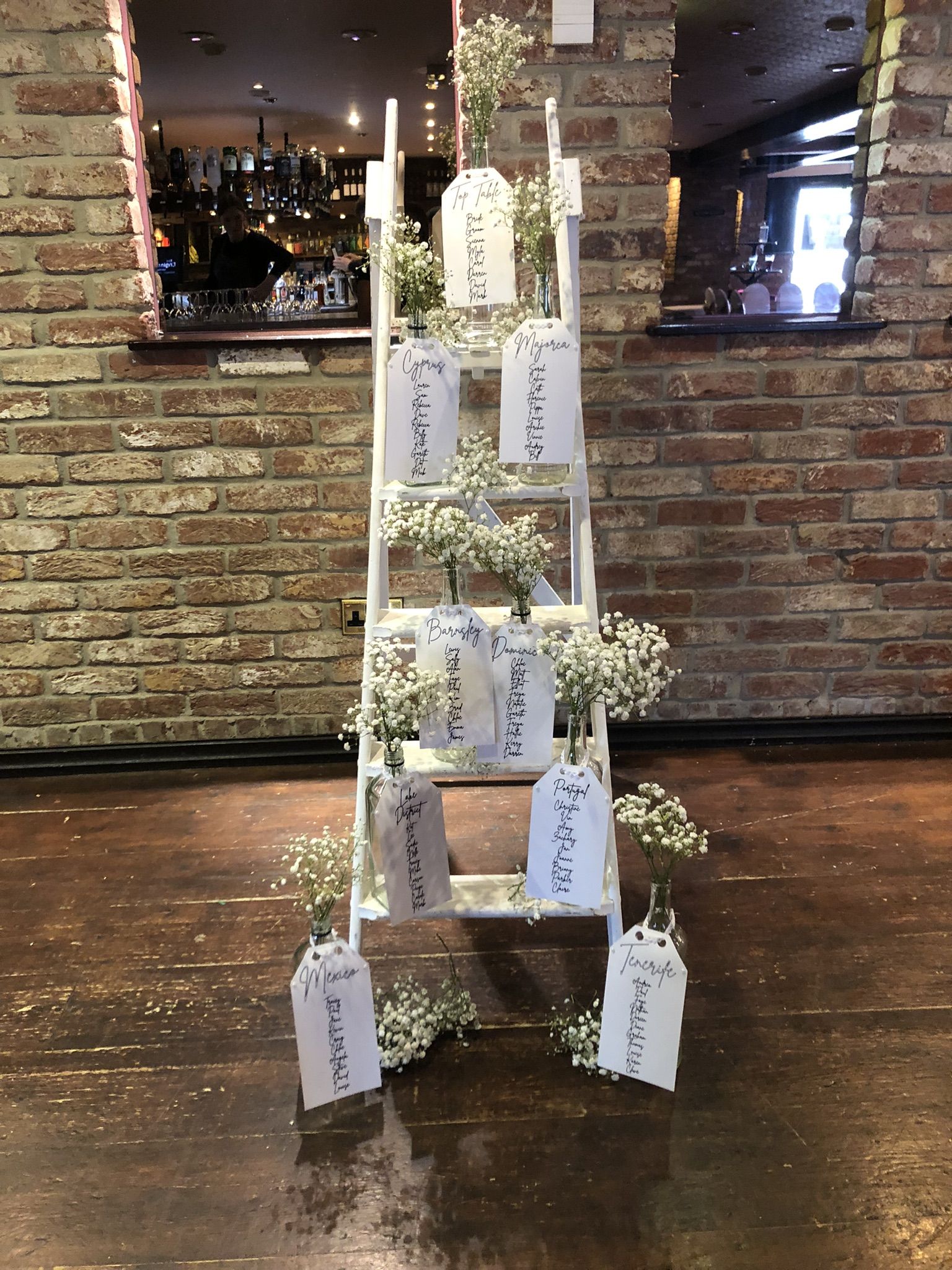 a ladder decorated with flowers and place cards.