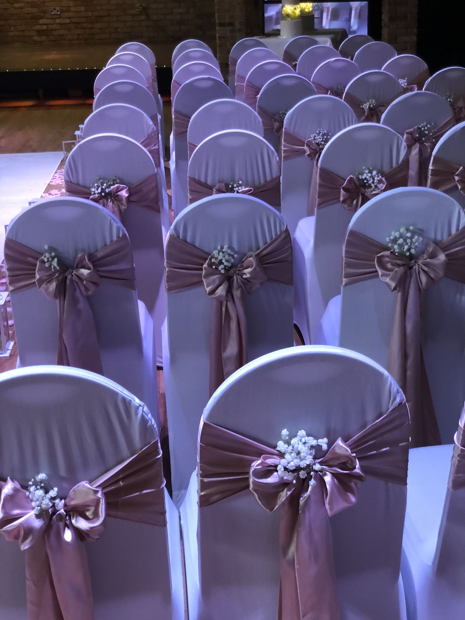 rows of chairs covered in purple sashes and bows.