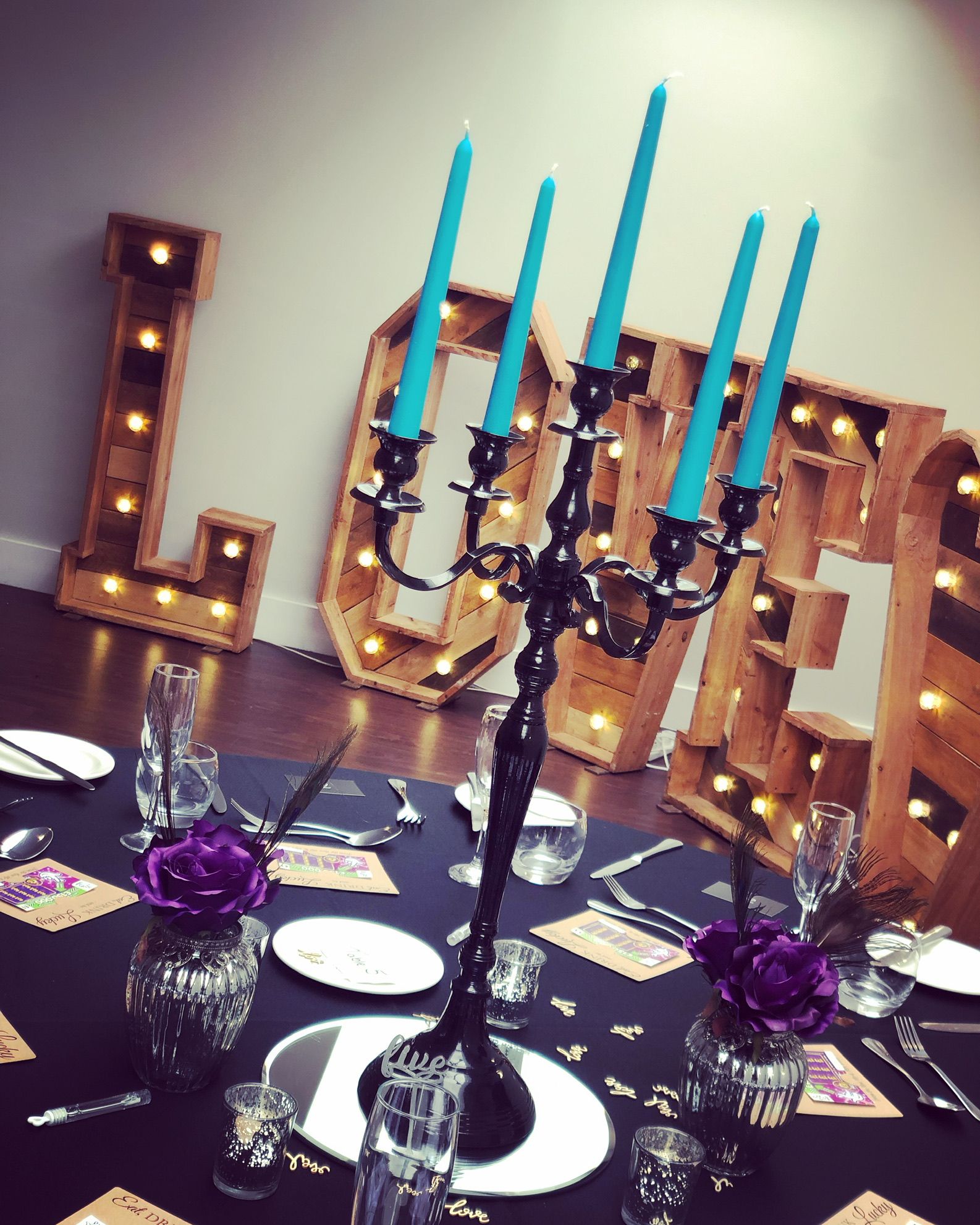 a table with a black table cloth and blue candles.