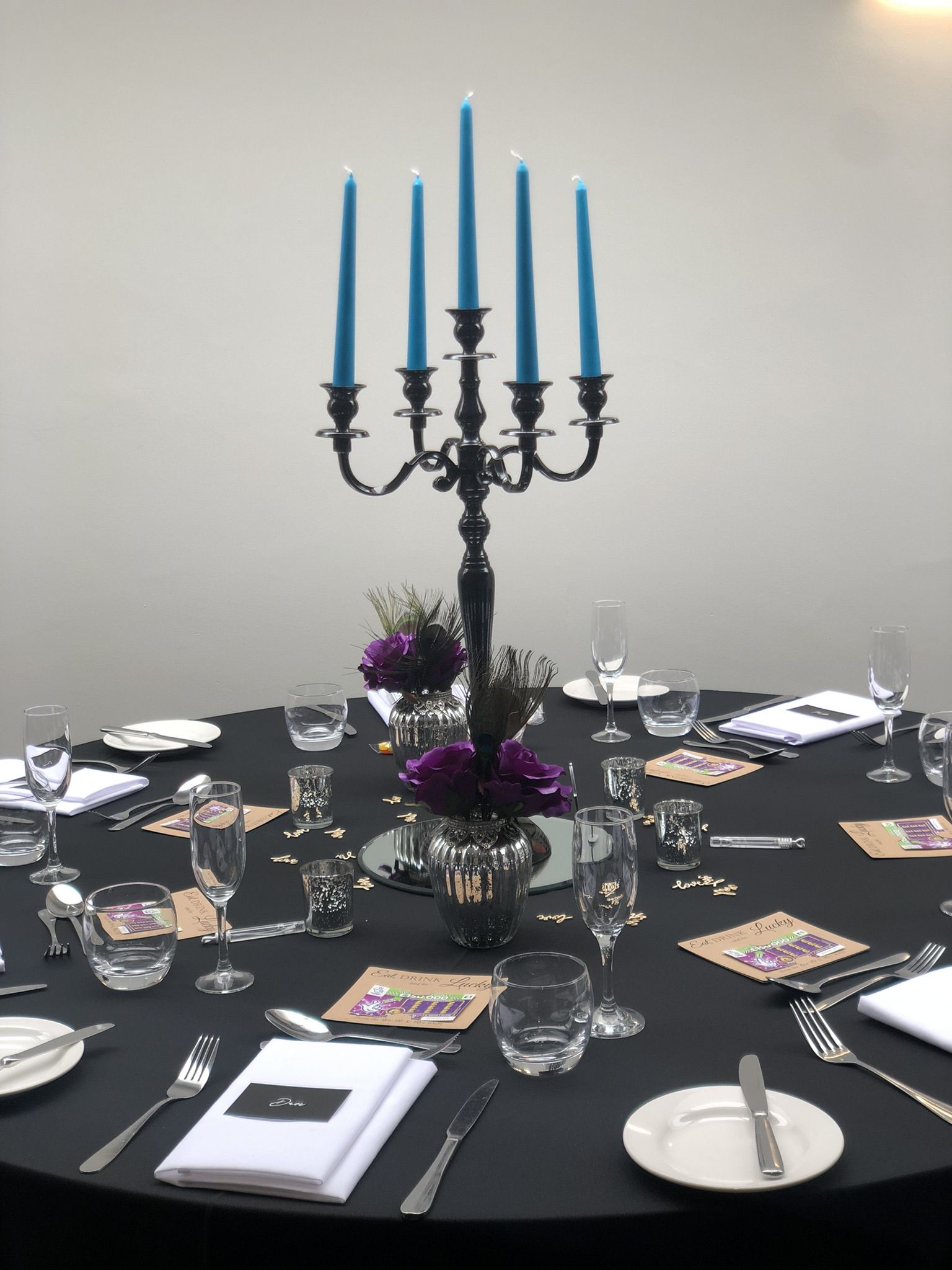 a table with a black table cloth and a candelabra with blue candles.