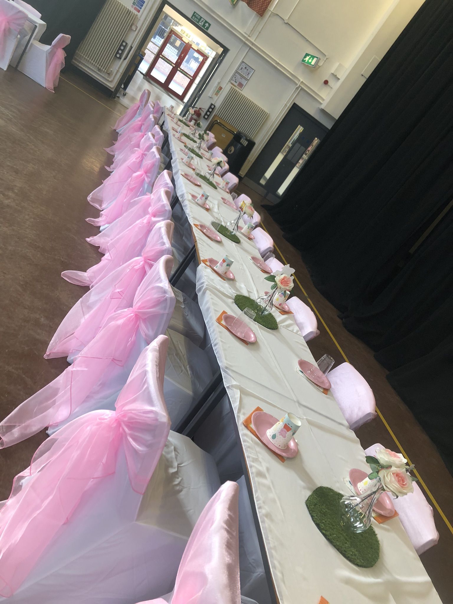 a row of tables with pink and white chairs.