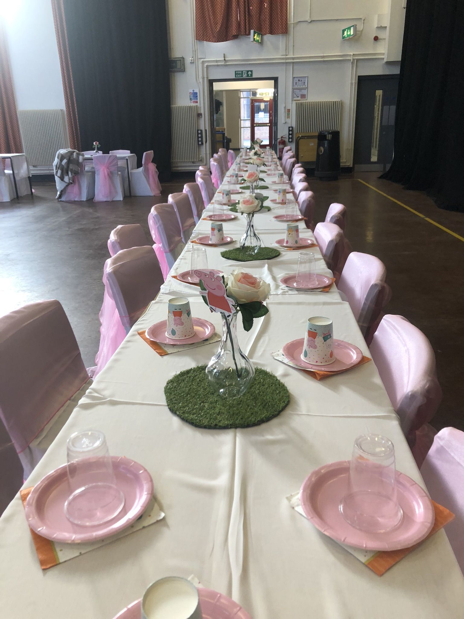 a long table is set with pink and white plates.