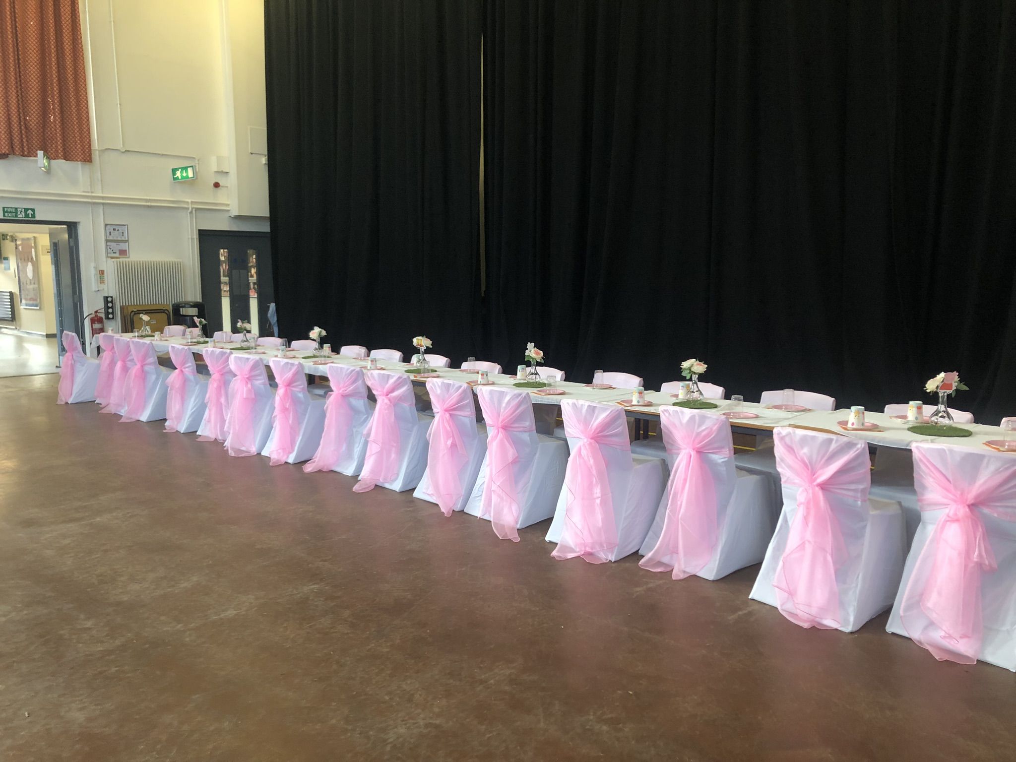 a long table covered in pink and white chairs.