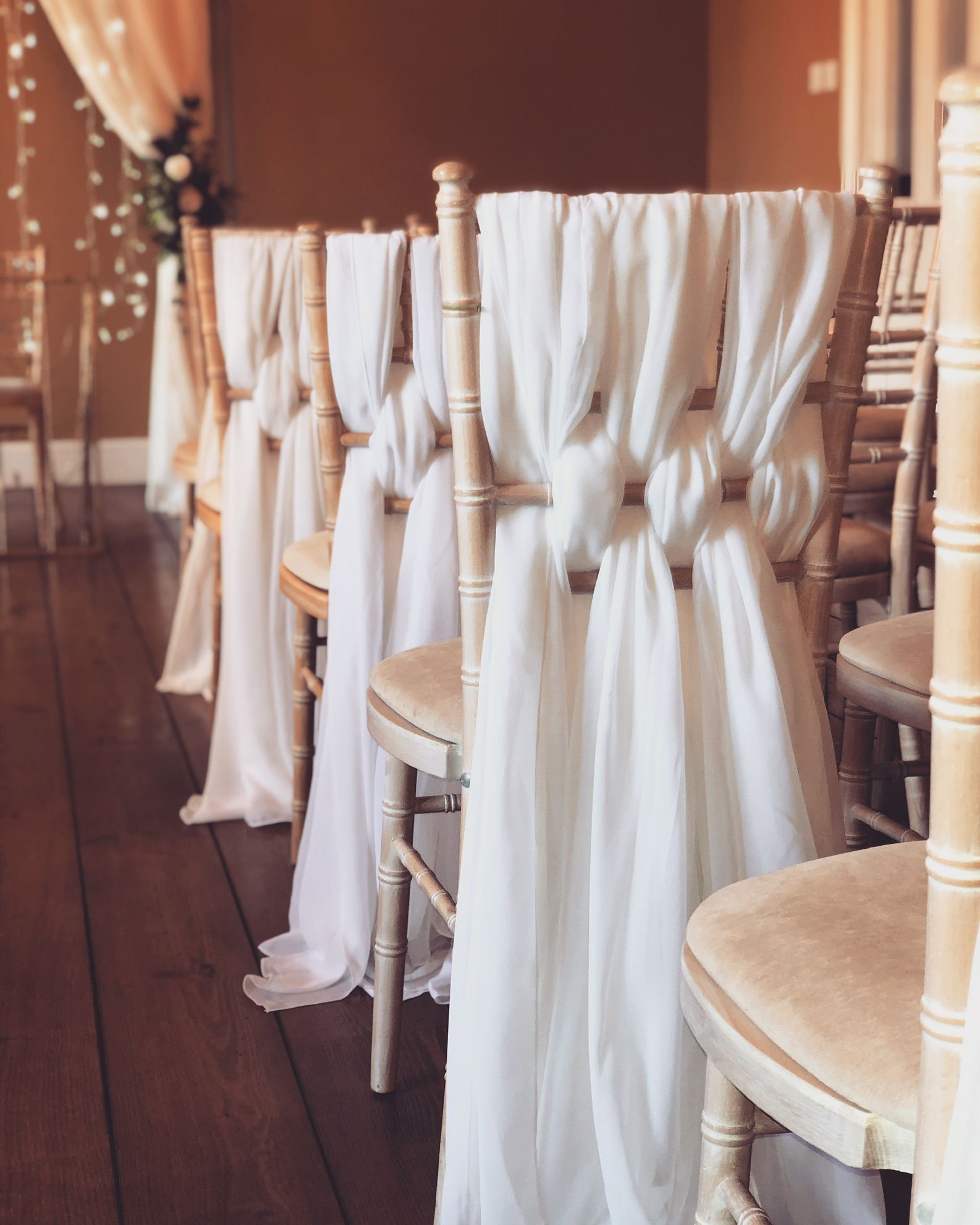 a row of chairs with white drapes on them.