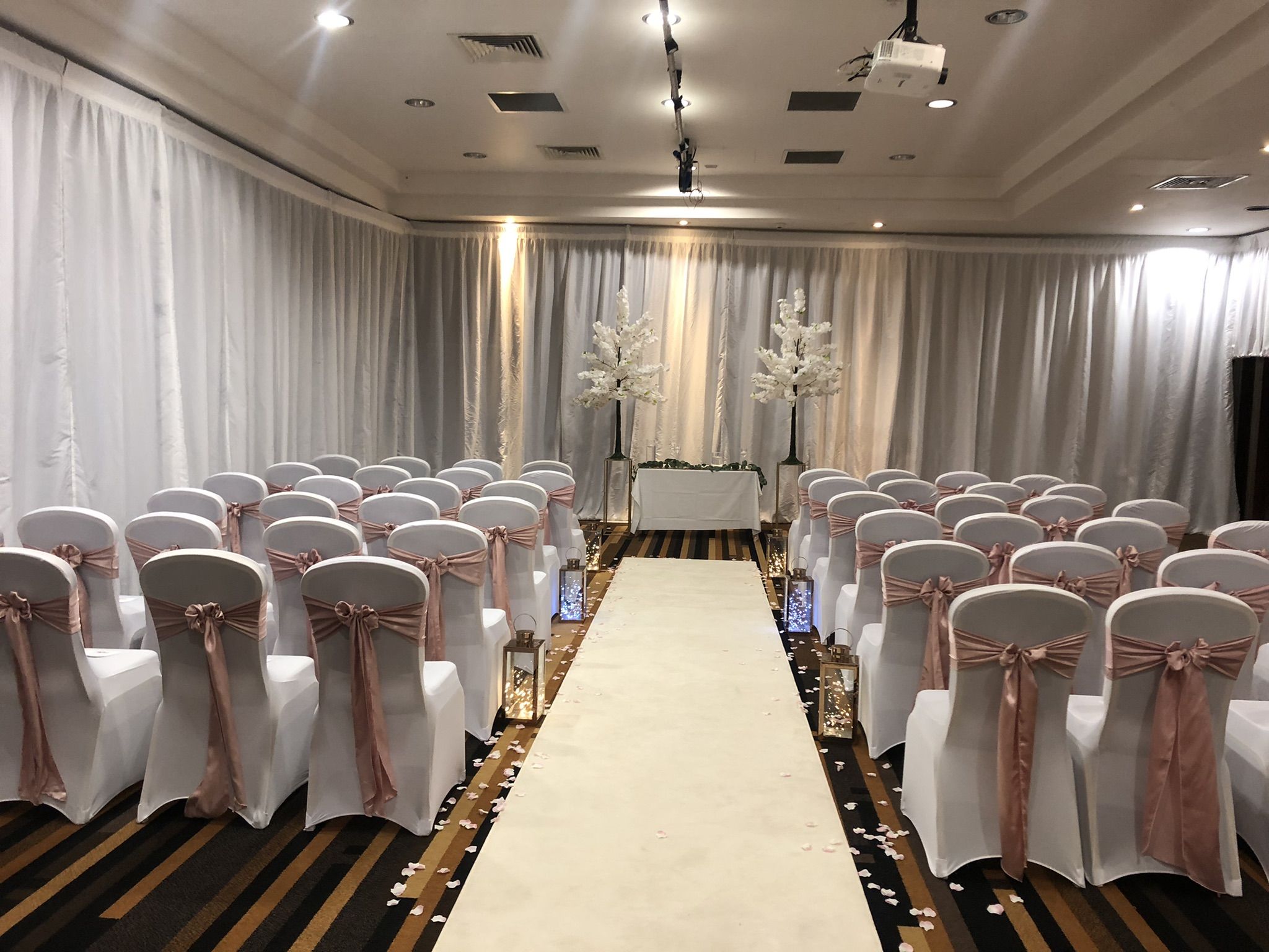 a long aisle lined with white and pink chairs.