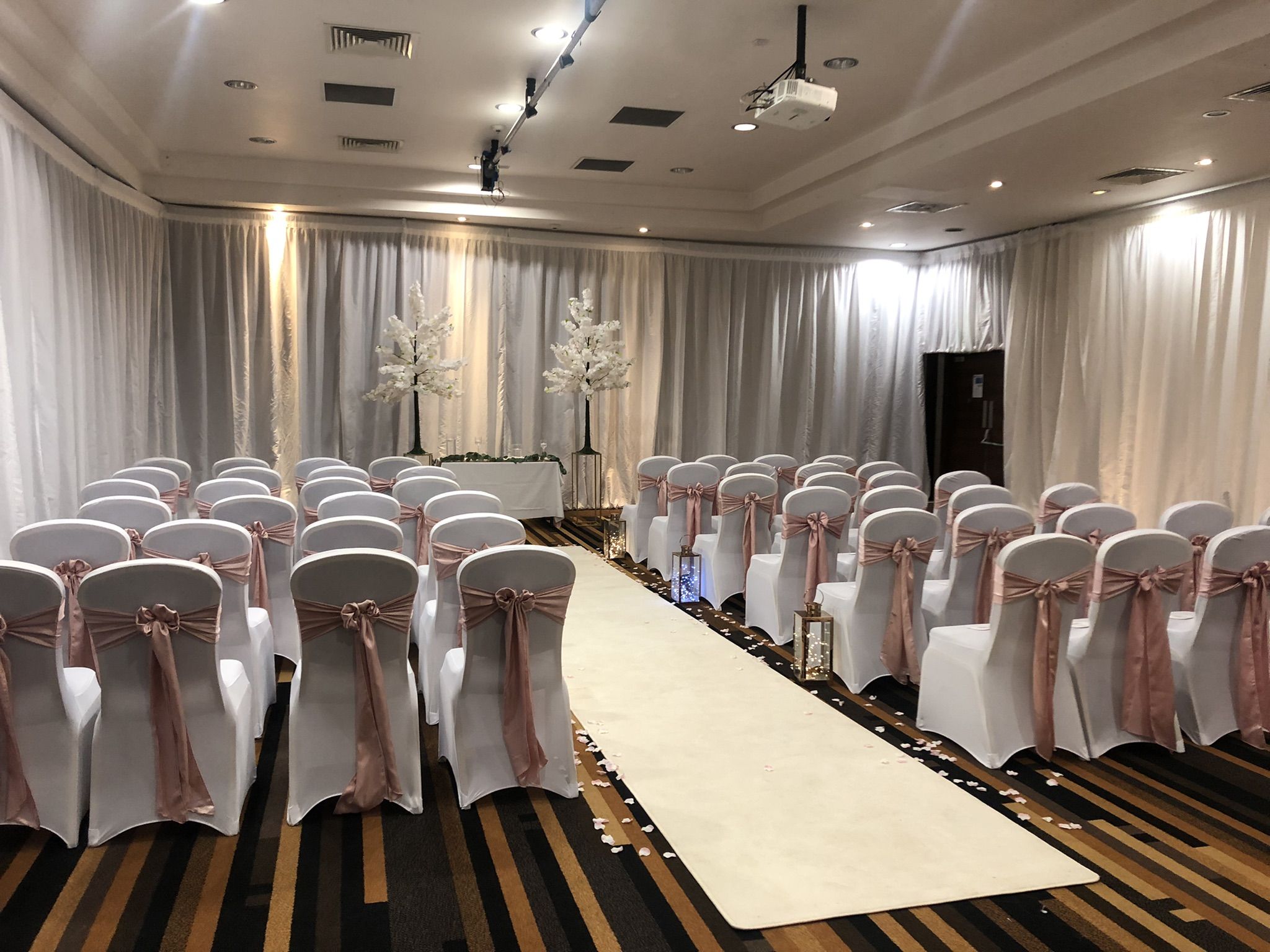 a banquet hall with rows of chairs and a white aisle.