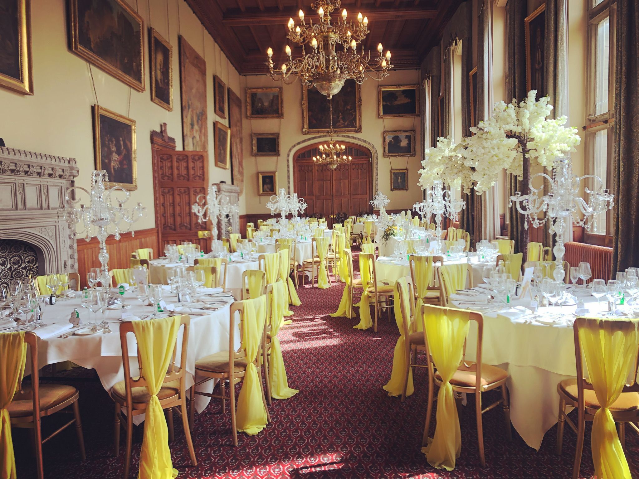 a dining room with tables and chairs covered in yellow cloths.