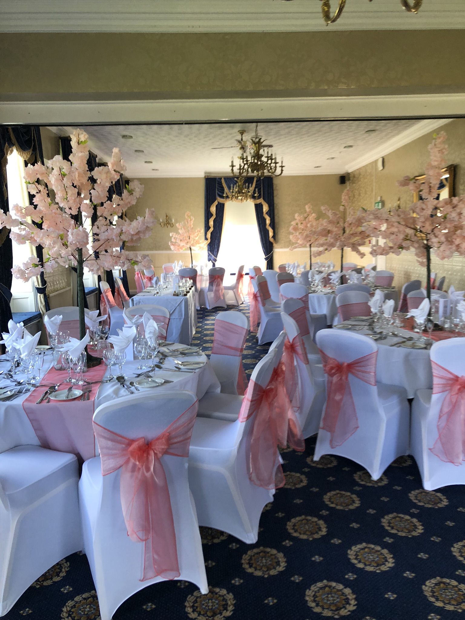 a room filled with tables covered in white and pink cloths.